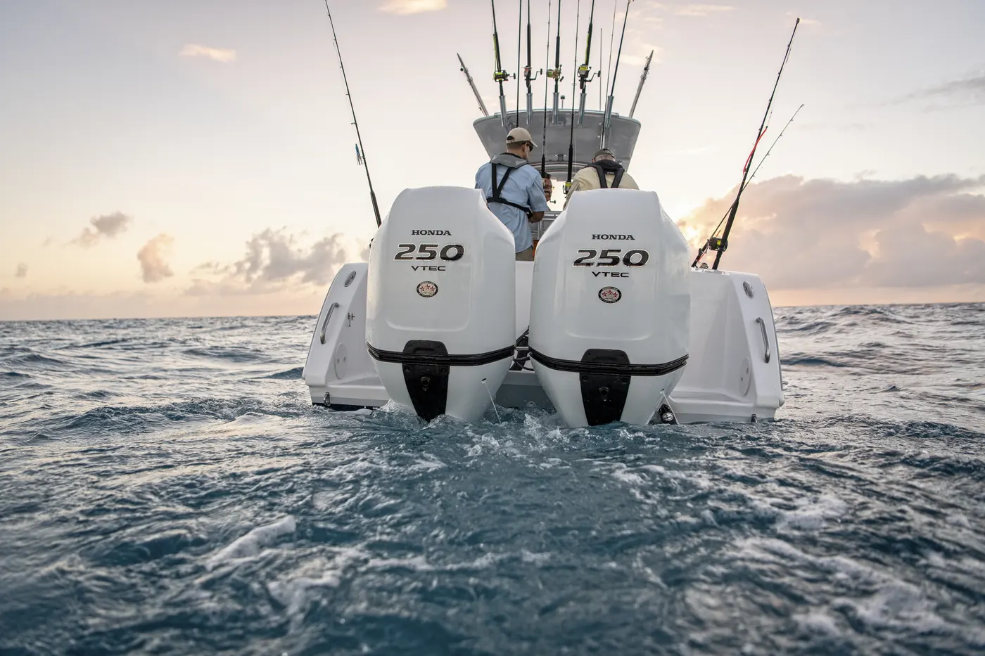 Twin white outboard motors running at sea at sunrise