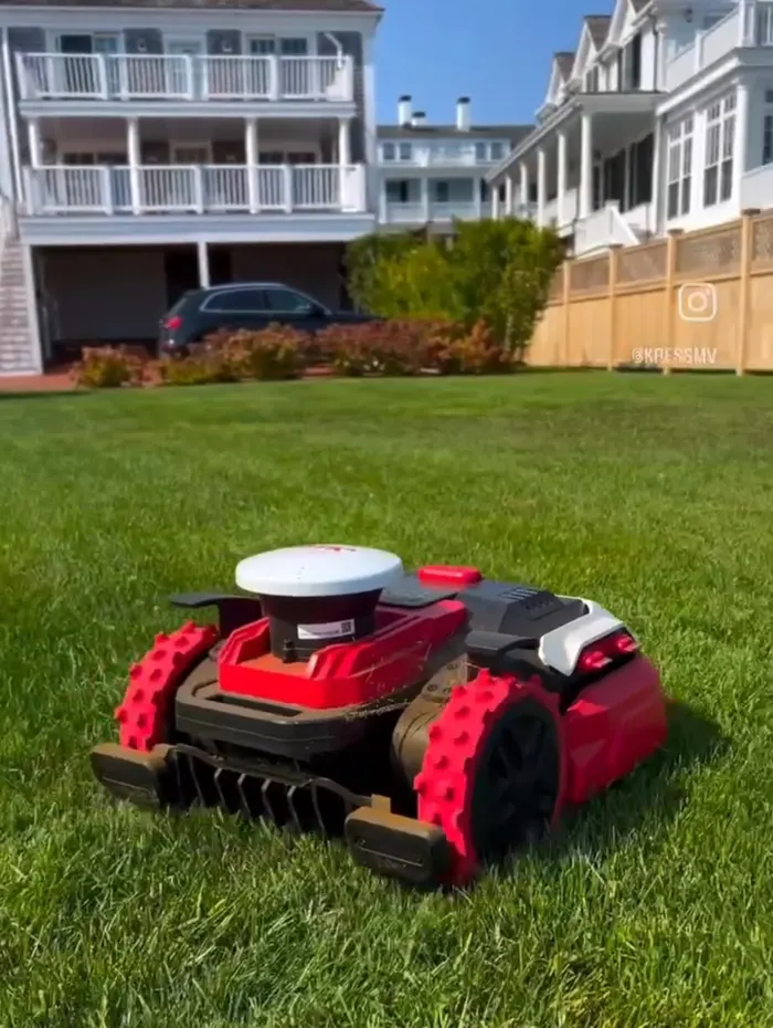 Red robotic mower on a lawn