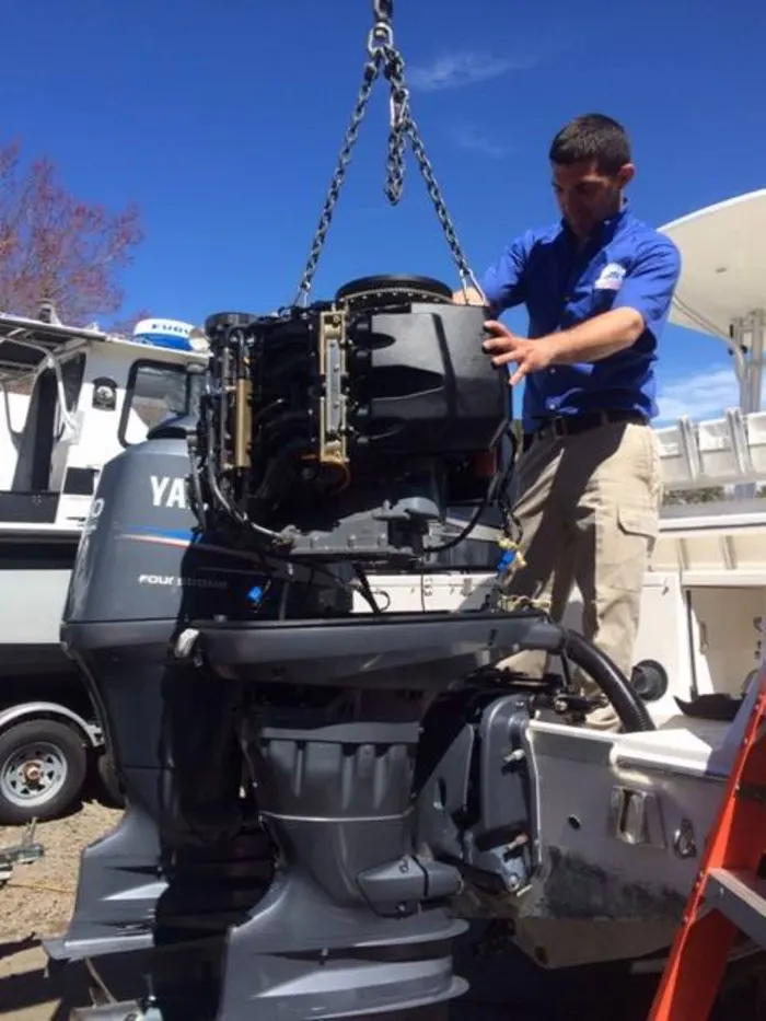 Technician lifting an outboard motor with a hoist
